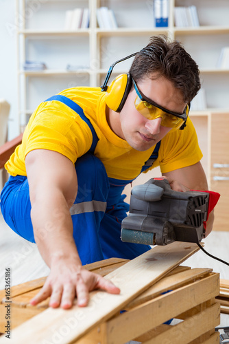 Repairman carpenter polishing a wooden board with an electric po