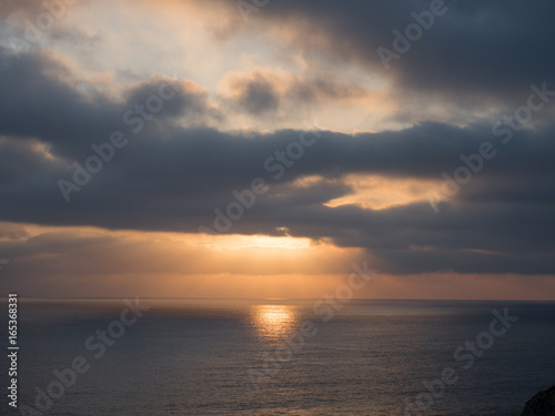 Beams of sunlight show through a cloudy sky onto the ocean