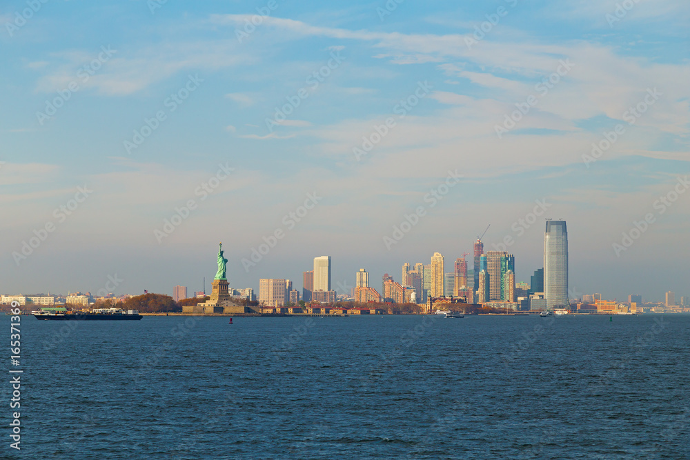 Fototapeta premium Lower Manhattan panorama and statue of Liberty in New York at dusk. Urban landscape of USA largest city from the river.