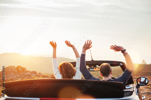 A loving couple enjoying the sunset and having fun in a convertible