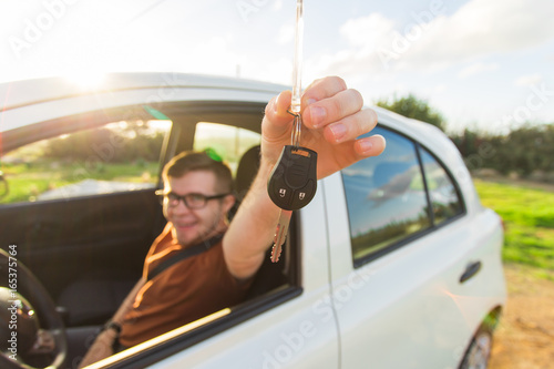 Excited young man showing a car key inside his new vehicle