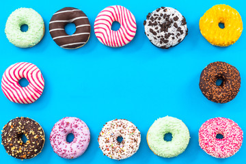 Colorful donuts border background, top view flat lay