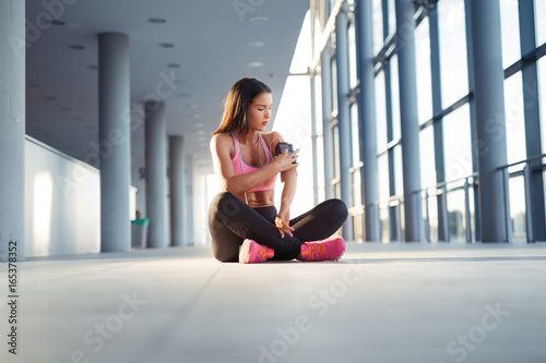 Young woman with earphones listening to music after hard workout