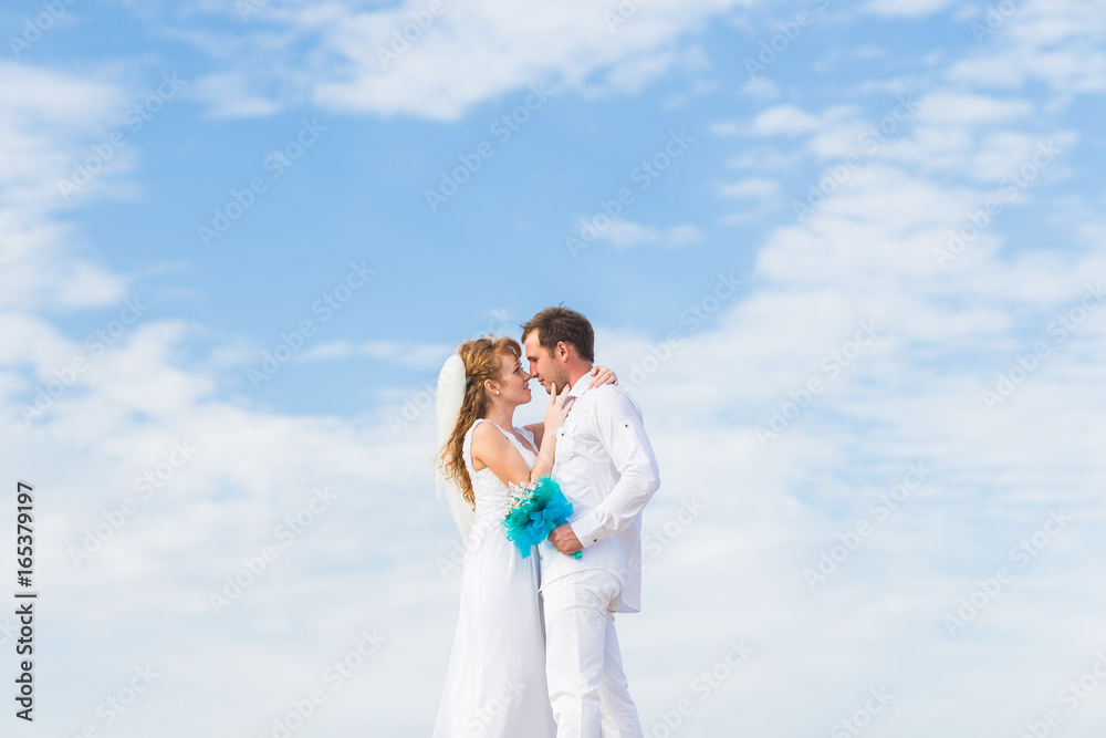Elegant stylish happy bride and gorgeous groom on the background of the blue sky