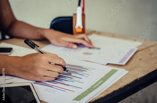 Businesswomen analyzing investment charts on the desk. Pen in hand
