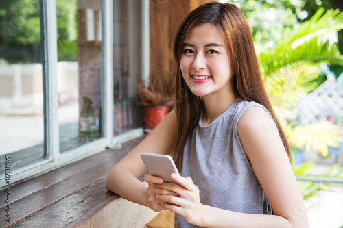 Asian beautiful woman smiling and holding mobile phone