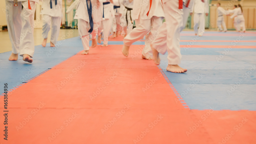 Karate training - young sportsmen in kimono runs on tatami in the gym