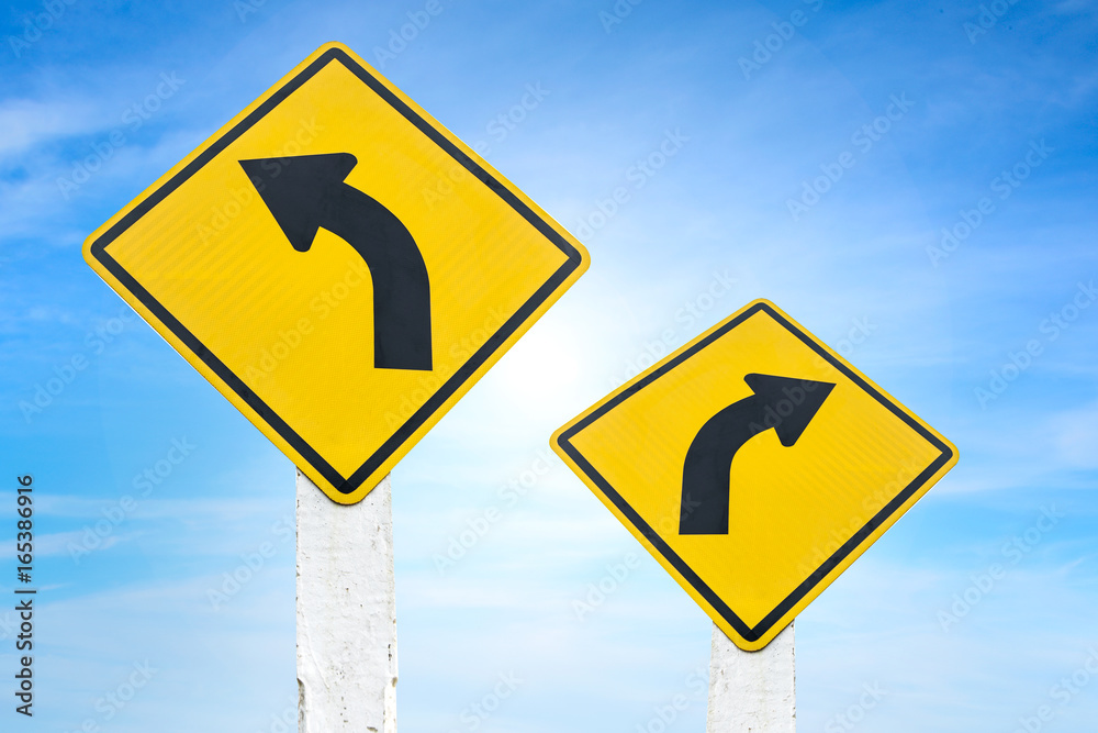 Yellow road signs indicating left and right turn with blue sky background. Yellow road signs indicating left and right turn with blue sky background.