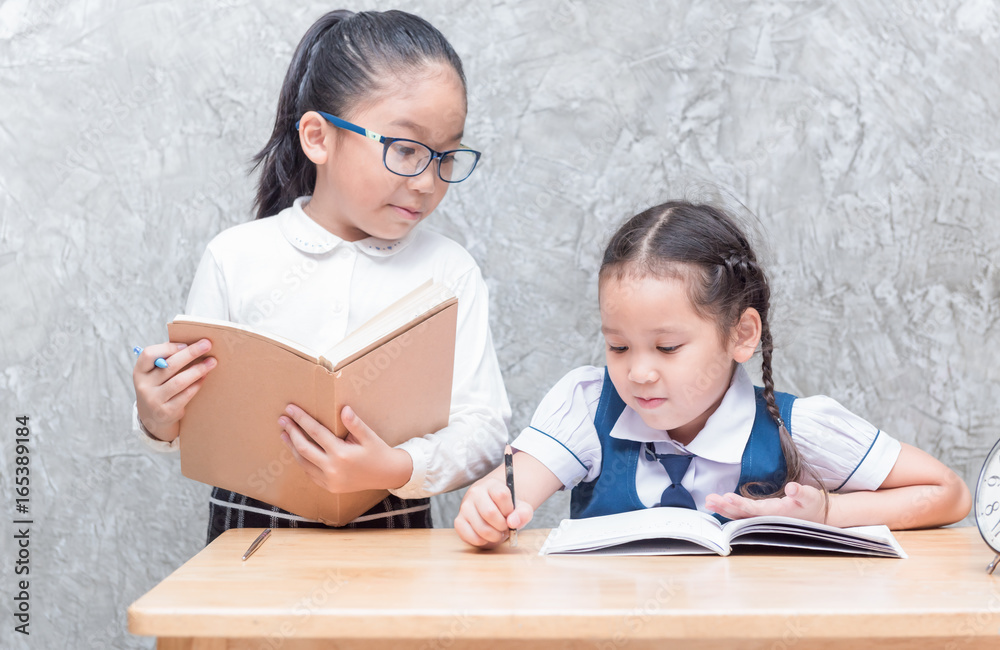 Cute asian girl student in uniform writing her homework Cute asian girl student in uniform writing her homework