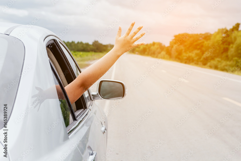 Naklejka premium Woman hand in the car relaxing and happy traveler on the road