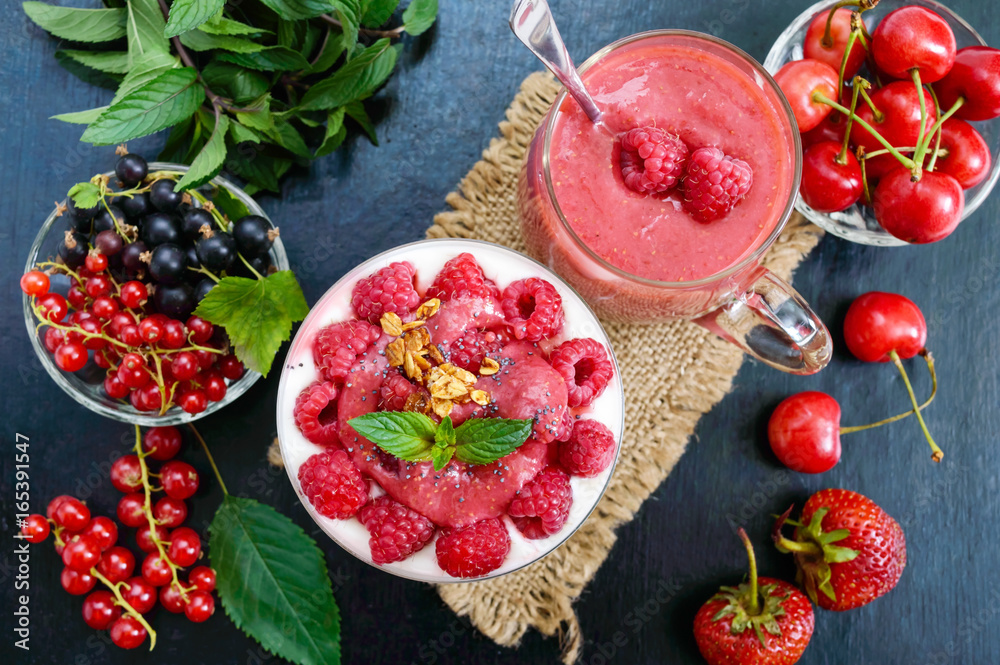 Delicious healthy dessert: yoghurt, fresh berries, granola, raspberry sauce on a black background. The top view