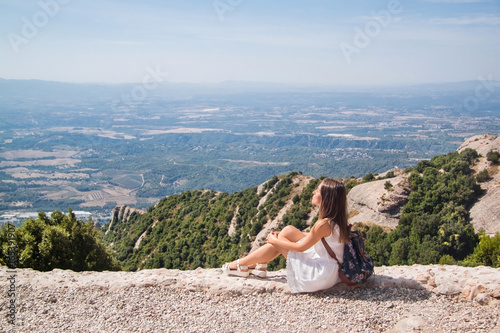 Young woman with backpack enjoying the view in Montserrat mountain on a hot summer day