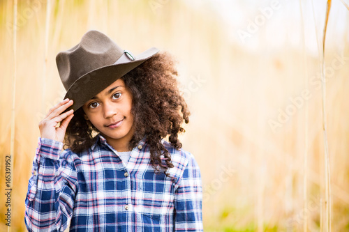 African american girl in checked shirt outdoors in field. © Halfpoint