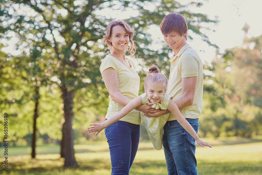 Fototapeta premium Happy family in the park on a tree background.