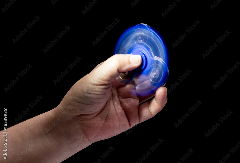 Spinning fidget spinner toy in human left hand isolated on black background. Super popular device. Spinning fidget spinner toy in human left hand isolated on black background. Super popular device.