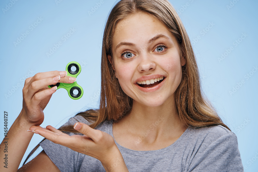 Young beautiful woman on a blue background holds a spinner Young beautiful woman on a blue background holds a spinner