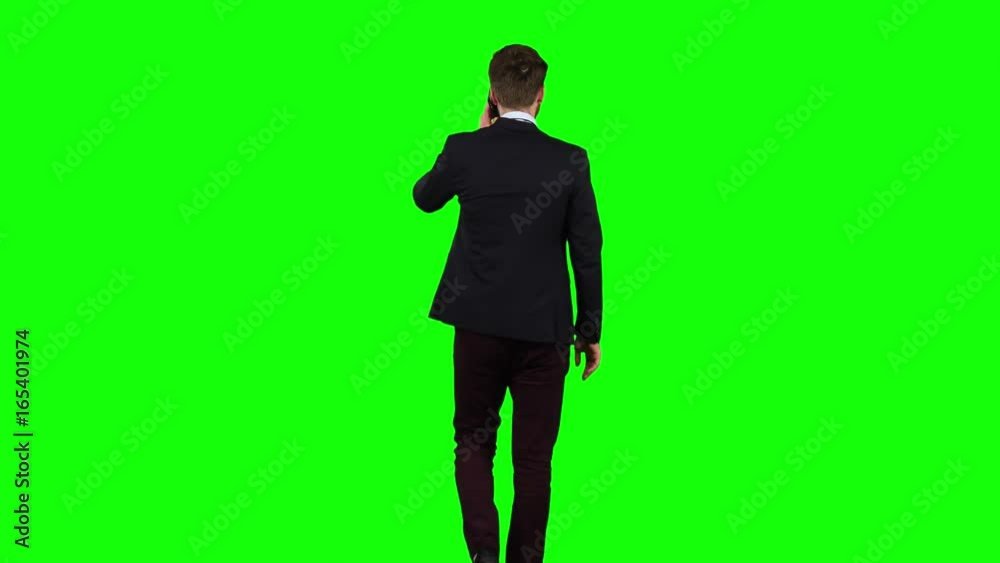 Man walks down the street, puts his hand in his pocket and waves. Green screen. Back view Man walks down the street, puts his hand in his pocket and waves. Green screen. Back view