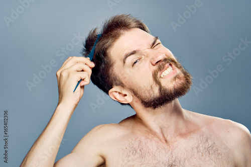 Man with a beard on a gray background combing
