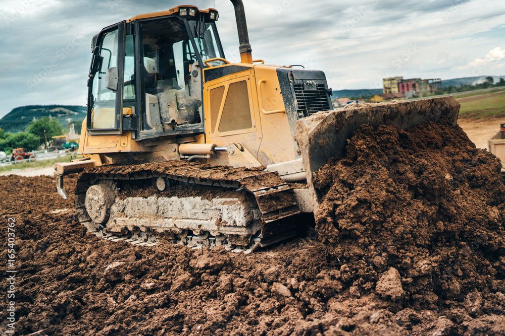 highway construction site with mini bulldozer pushing earth and leveling ground