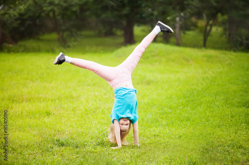 Active little school girl somersault outdoors