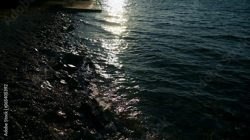 waves hitting sandy beach at sunset with sun reflection in slow motion hd photo