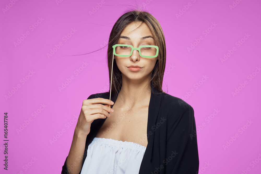 Young beautiful woman on a pink background holds paper accessories for parties and holidays Young beautiful woman on a pink background holds paper accessories for parties and holidays