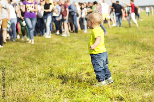 One year boy looking at the crowd on a rock festival.