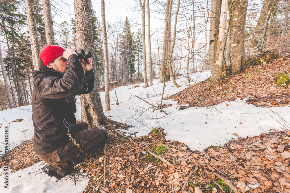 man with binoculars in the forest - outdoor activity italian Alps Italy man with binoculars in the forest - outdoor activity italian Alps Italy
