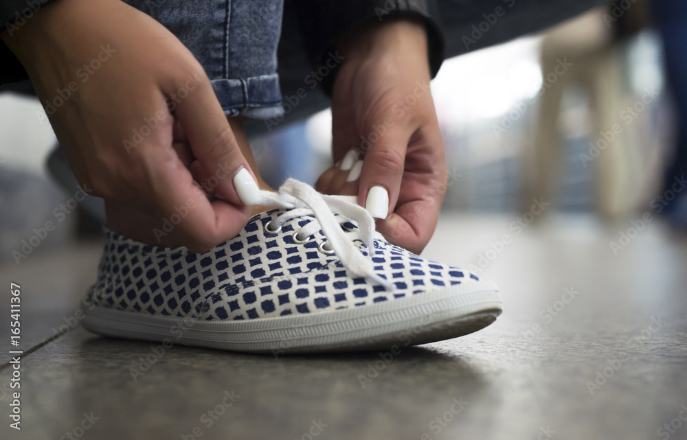 Fototapeta premium Girl ties up shoelaces on sneakers