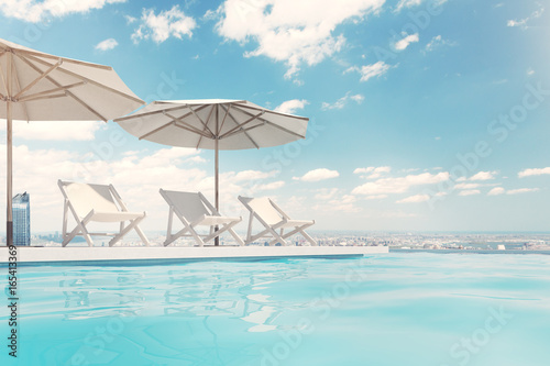 Fototapeta Naklejka Na Ścianę i Meble -  Swimming pool with deck chairs, umbrellas, sky