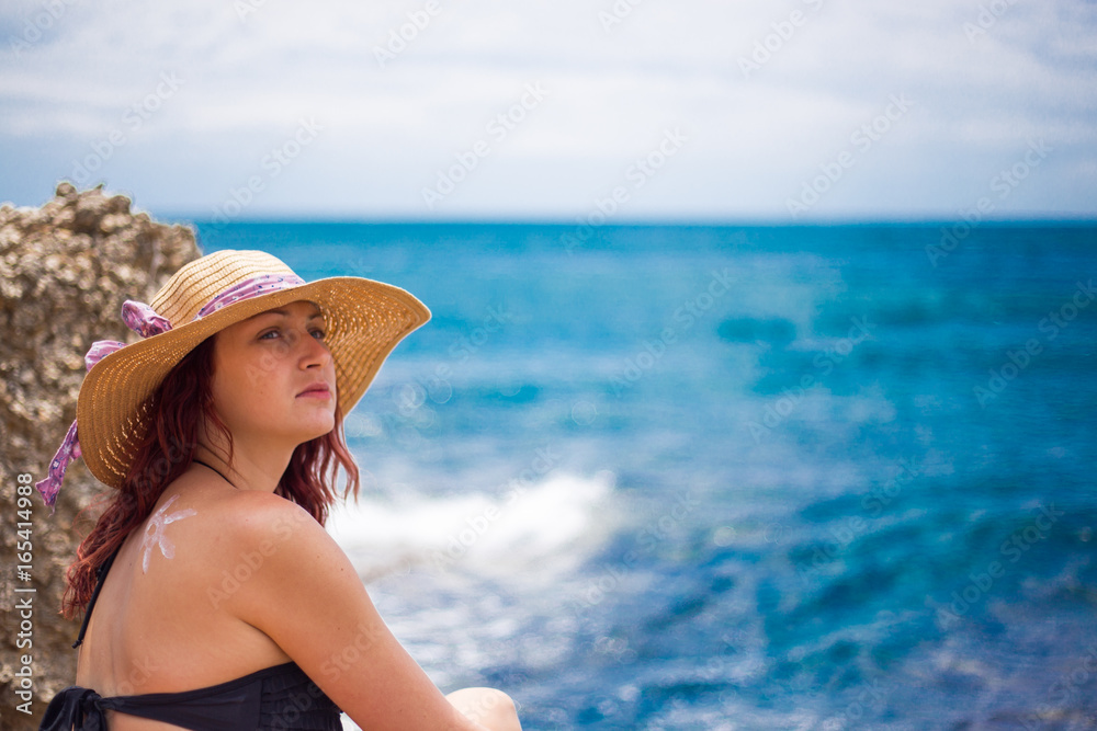 A young girl on a beach with a hat, sun and enjoys the sun, on the shoulder drawn sun from sun cream, summer, sun, sea