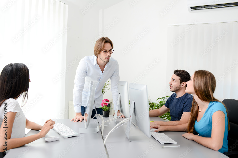 Fototapeta premium four creative people discussing in a classroom of business school with desktop computer