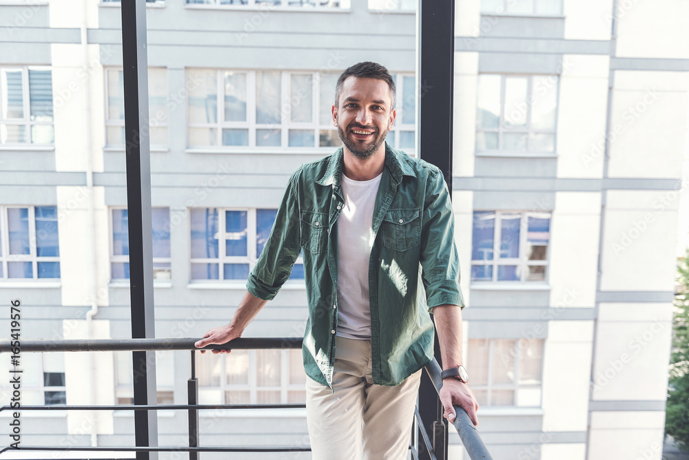 Cheerful stylish guy is standing on staircase Cheerful stylish guy is standing on staircase