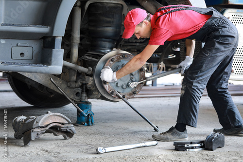 A mechanic repairs a truck. Replace brake disc and pads © kot500