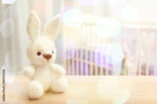 Cute crochet bunny baby toy on table in bedroom