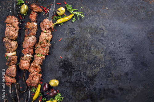 Traditional Russian shashlik on a barbecue skewer as top view with copy space on old rusty metal sheet photo