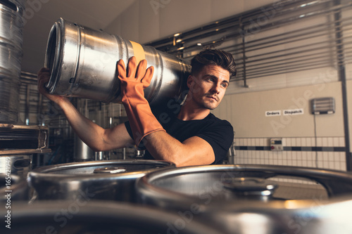 Tableau sur toile Brewer carrying keg at brewery factory