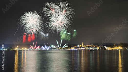 Fireworks on the lake in a summer night with city in the background