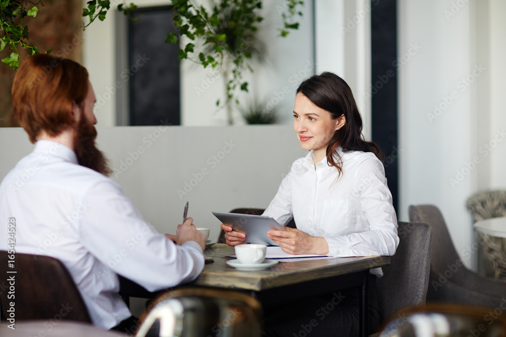 Two contemporary managers having meeting in cafe
