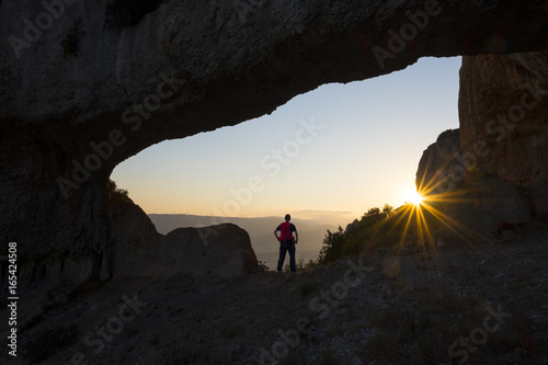 Young man in arch rock to ascension to the top