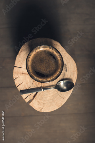 top view of glass of coffee drink and spoon on wood log