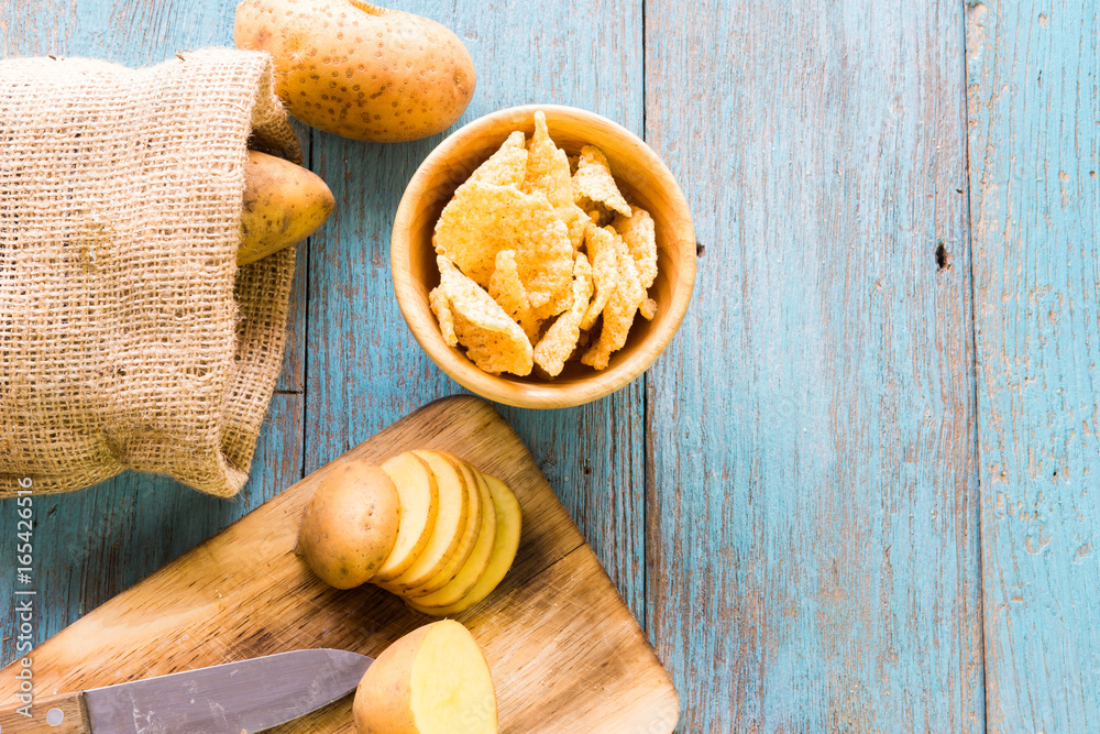 Pile of potatoes lying on wooden boards with a potato bag in the background Pile of potatoes lying on wooden boards with a potato bag in the background