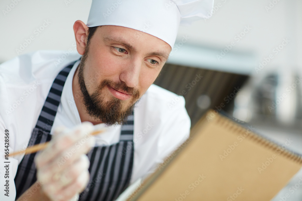 Chef writing recipe or menu of the day Chef writing recipe or menu of the day