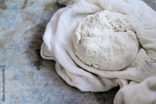 Fresh cooking homemade cottage cheese in gauze textile over gray metal background. Rustic style, day light