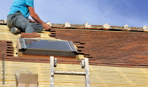 couvreur posant tuiles sur toiture avec fenêtre de toit 