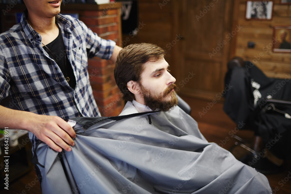Hairdresser preparing client for haircutting Hairdresser preparing client for haircutting