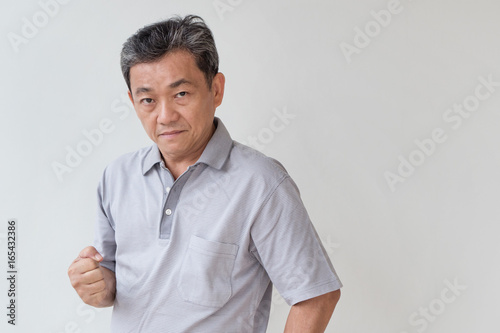 angry, upset, unhappy, frustrated, unfriendly middle age old asian man looking at you © 9nong