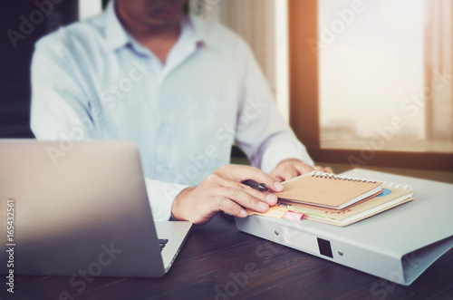 Fototapeta Naklejka Na Ścianę i Meble -  businessman hand working laptop on wooden desk in office in morning light. The concept of modern work with advanced technology. vintage effect