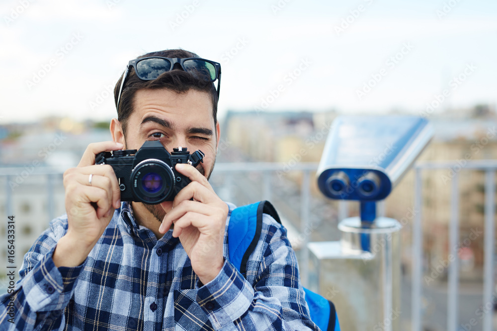 Obraz premium Portrait of handsome young man taking picture with vintage photo camera