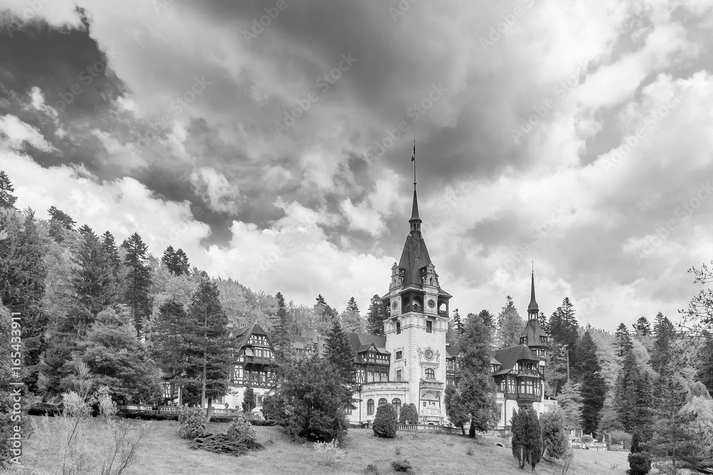 Beautiful black and white view of the famous Peles Castle, Sinaia, Romania, with the Romanian flag flying on top of a spire